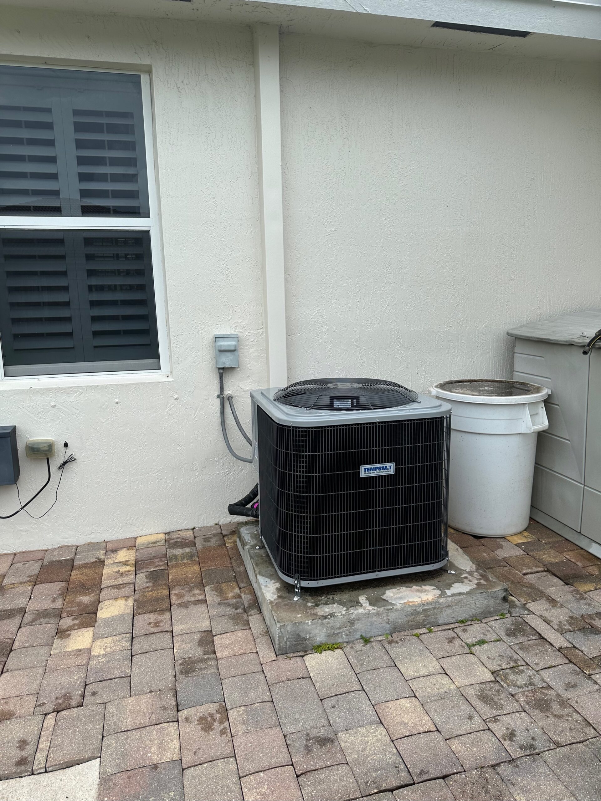 HVAC technician inspecting an outdoor air conditioning unit showing AC compressor failure signs before a complete breakdown.